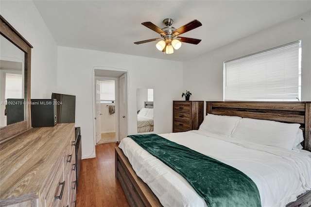 bedroom with hardwood / wood-style floors, ensuite bathroom, and ceiling fan