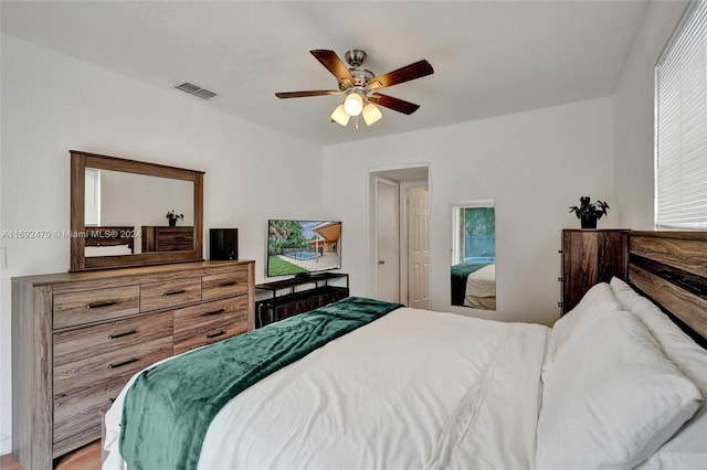 bedroom with hardwood / wood-style flooring, ceiling fan, and multiple windows