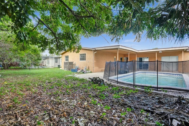 back of property featuring a fenced in pool and a lawn