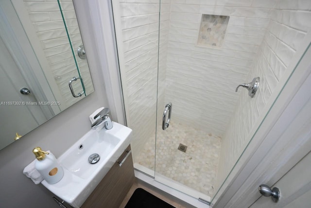 bathroom featuring a shower with door and vanity