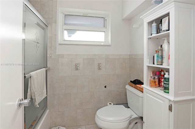 bathroom featuring toilet, tile walls, and enclosed tub / shower combo