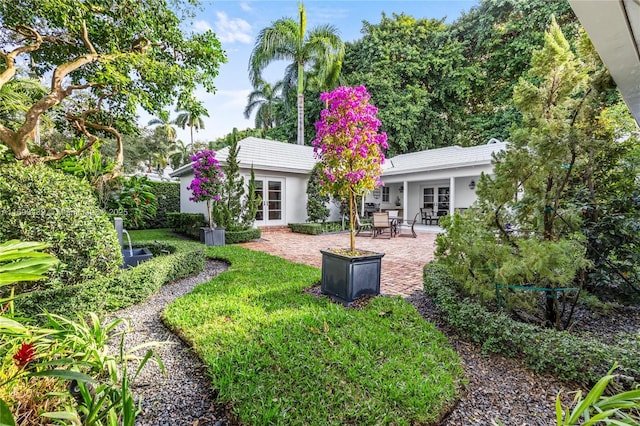 back of property featuring french doors, a yard, and a patio