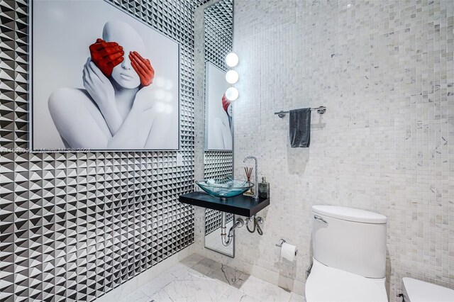 bathroom featuring sink, tile walls, and toilet