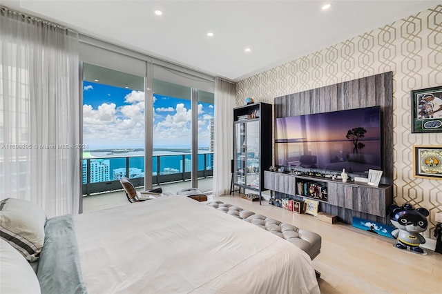 bedroom with access to outside, hardwood / wood-style floors, and a wall of windows