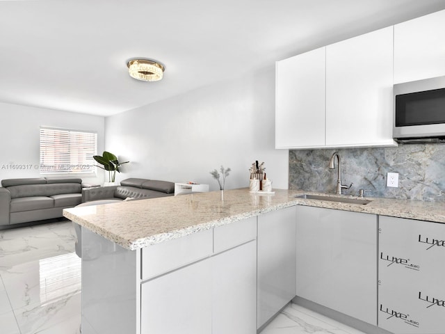 5390 W 21st Ct Unit 312, Hialeah, FL 33016 - kitchen with a sink, stainless steel microwave, light marble finish flooring, a peninsula, and backsplash