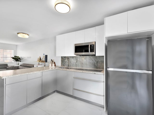 kitchen featuring sink, white cabinetry, stainless steel appliances, kitchen peninsula, and decorative backsplash