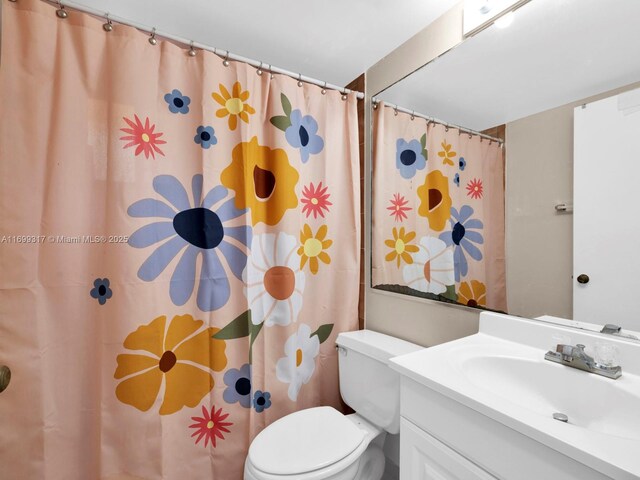 bathroom featuring a shower with shower curtain, vanity, and toilet