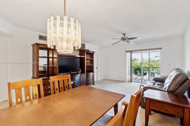 dining space with ceiling fan with notable chandelier and light colored carpet