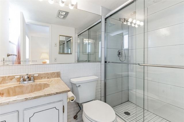 bathroom with tile patterned floors, vanity, tile walls, and toilet