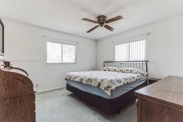 carpeted bedroom featuring ceiling fan, a textured ceiling, and multiple windows