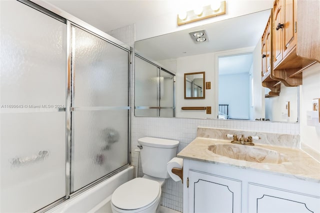 full bathroom featuring vanity, toilet, tile walls, and enclosed tub / shower combo