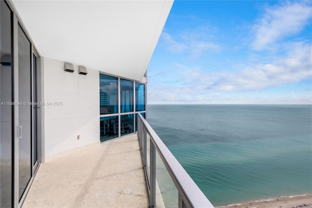 balcony with a water view and a view of the beach