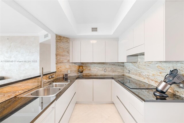 kitchen featuring backsplash, kitchen peninsula, light tile patterned floors, ornamental molding, and white cabinetry