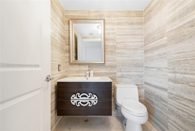 bathroom with toilet, vanity, tile walls, and tile patterned floors