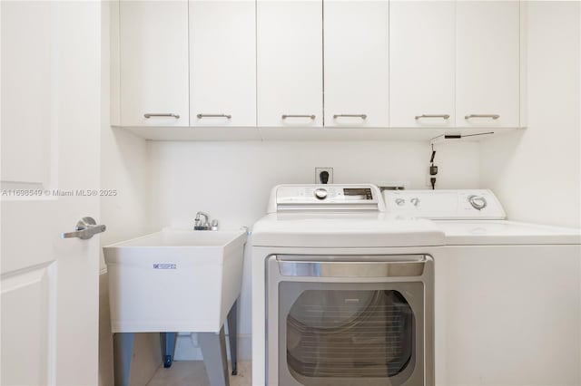 laundry room featuring cabinet space, washing machine and dryer, and a sink