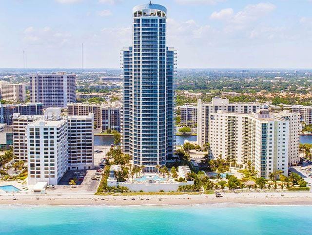 aerial view featuring a view of the beach, a water view, and a view of city