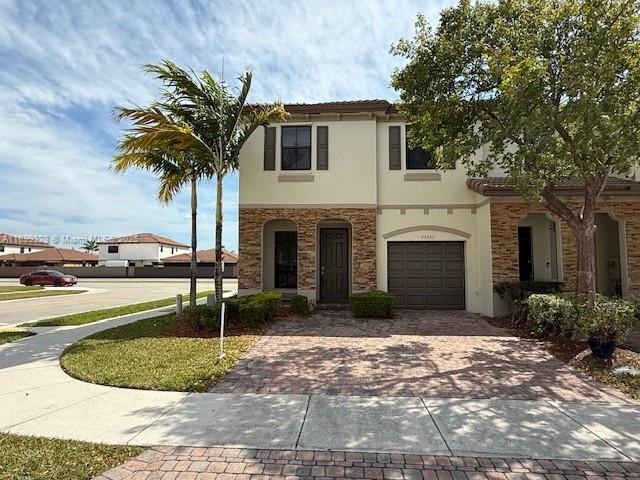 view of front facade featuring decorative driveway, a garage, and stucco siding