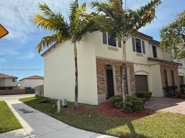 view of front of home with stucco siding, decorative driveway, and a garage