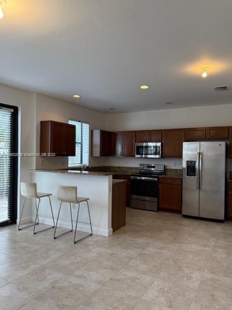 kitchen featuring dark countertops, visible vents, recessed lighting, appliances with stainless steel finishes, and a peninsula