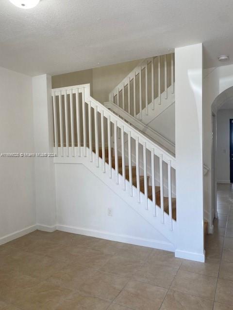 stairway with tile patterned flooring and a textured ceiling