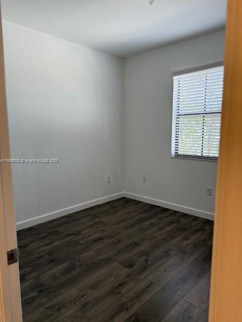 unfurnished room with baseboards and dark wood-style flooring