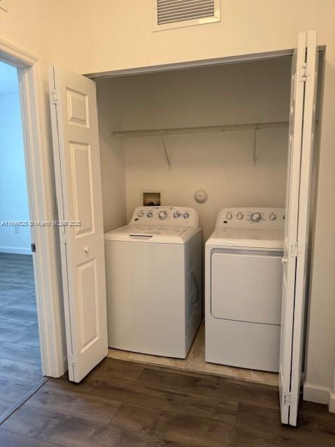 laundry area with visible vents, washing machine and dryer, dark wood-style flooring, and laundry area