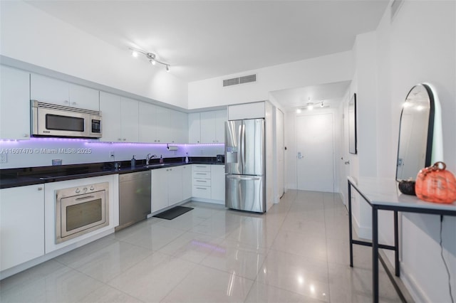 kitchen featuring visible vents, white cabinets, dark countertops, appliances with stainless steel finishes, and rail lighting