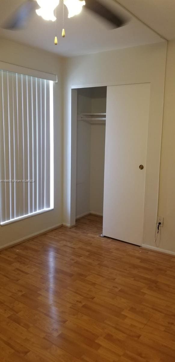 unfurnished bedroom featuring hardwood / wood-style floors, a closet, and ceiling fan