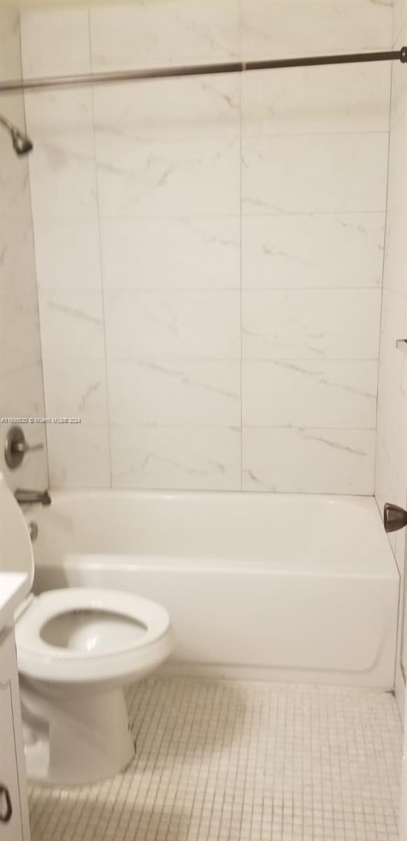 full bathroom featuring vanity, tiled shower / bath combo, and toilet