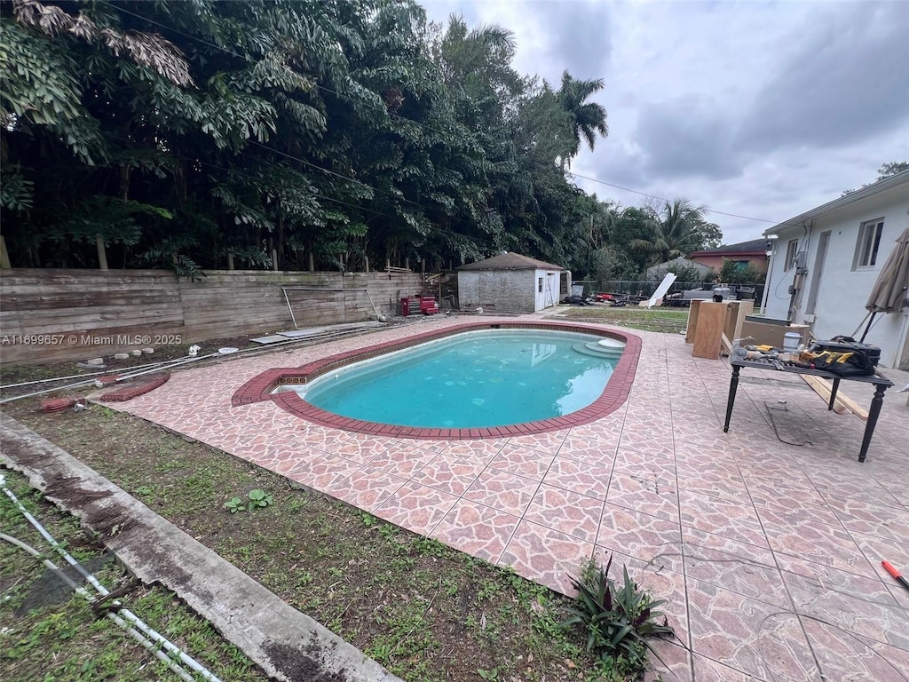 view of swimming pool featuring a storage unit and a patio area