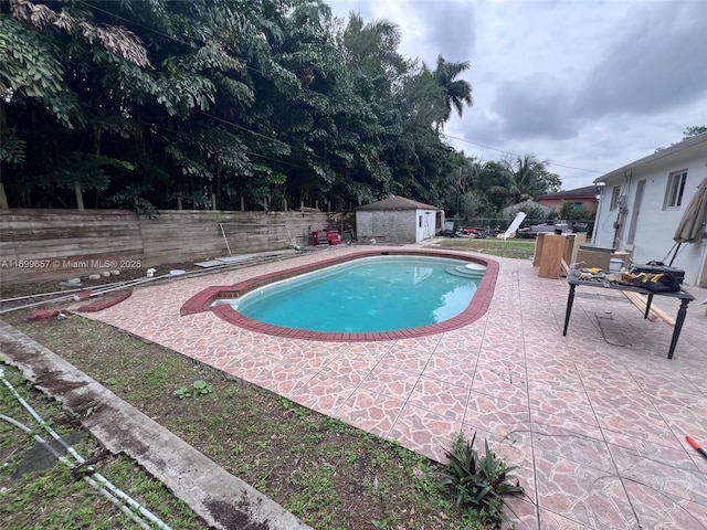 view of swimming pool featuring a storage unit and a patio area