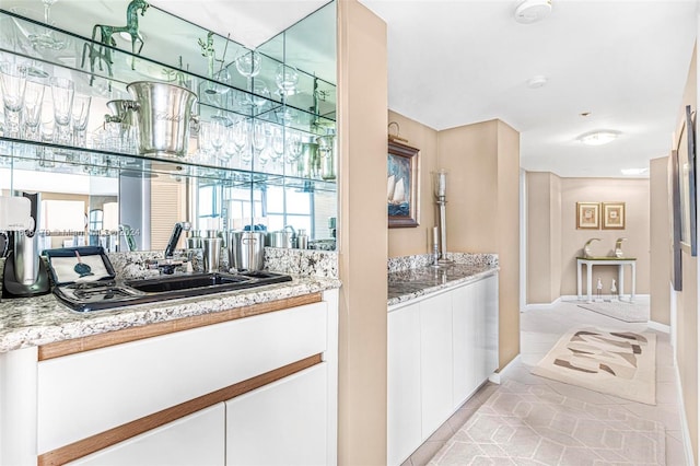 bar featuring white cabinetry, sink, light tile patterned flooring, and light stone countertops