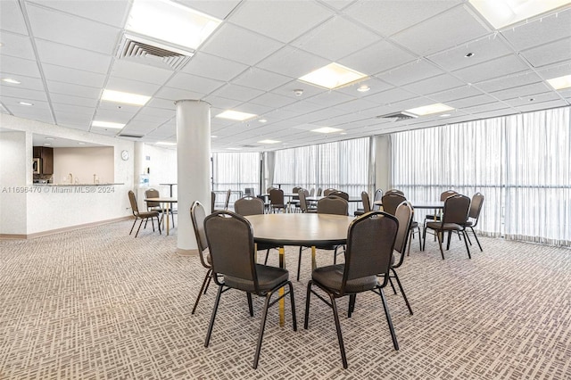 carpeted dining area featuring a paneled ceiling