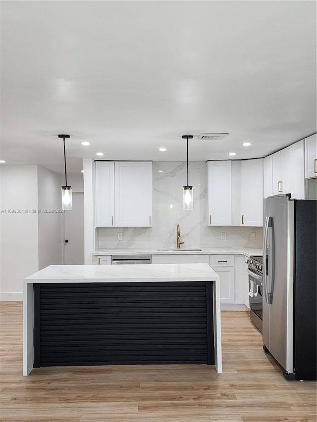 kitchen featuring white cabinets, decorative light fixtures, sink, and stainless steel appliances