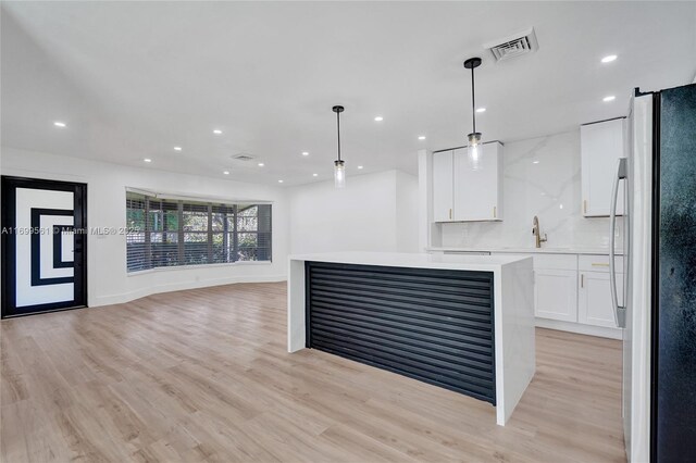 kitchen featuring white cabinets, decorative light fixtures, stainless steel appliances, and decorative backsplash