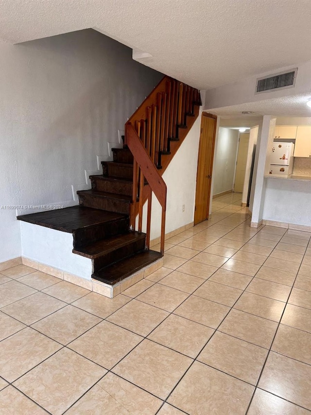 stairs featuring tile patterned floors, a textured ceiling, and vaulted ceiling