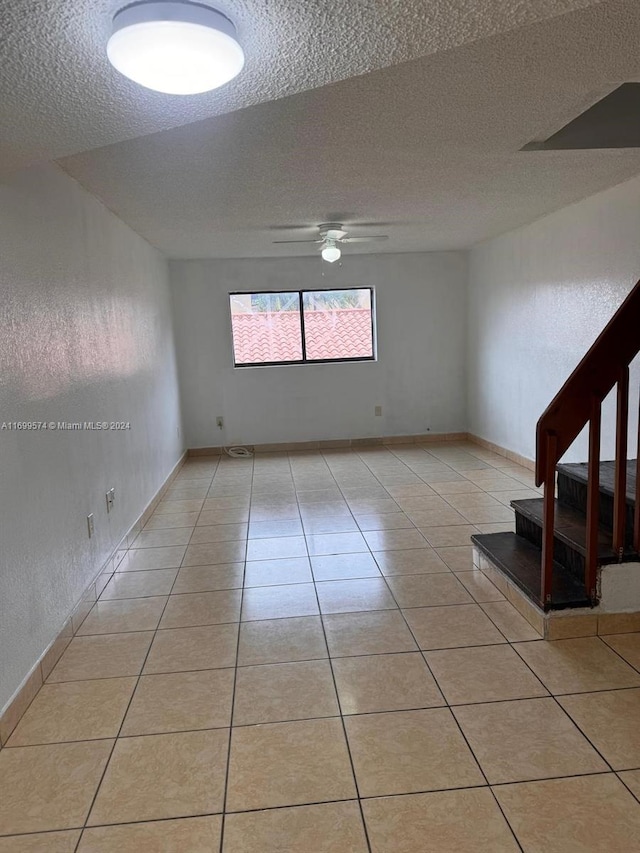 tiled spare room with ceiling fan and a textured ceiling