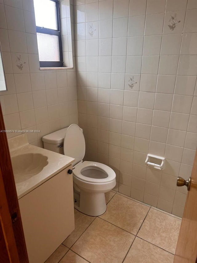 bathroom featuring toilet, vanity, tile patterned floors, and tile walls