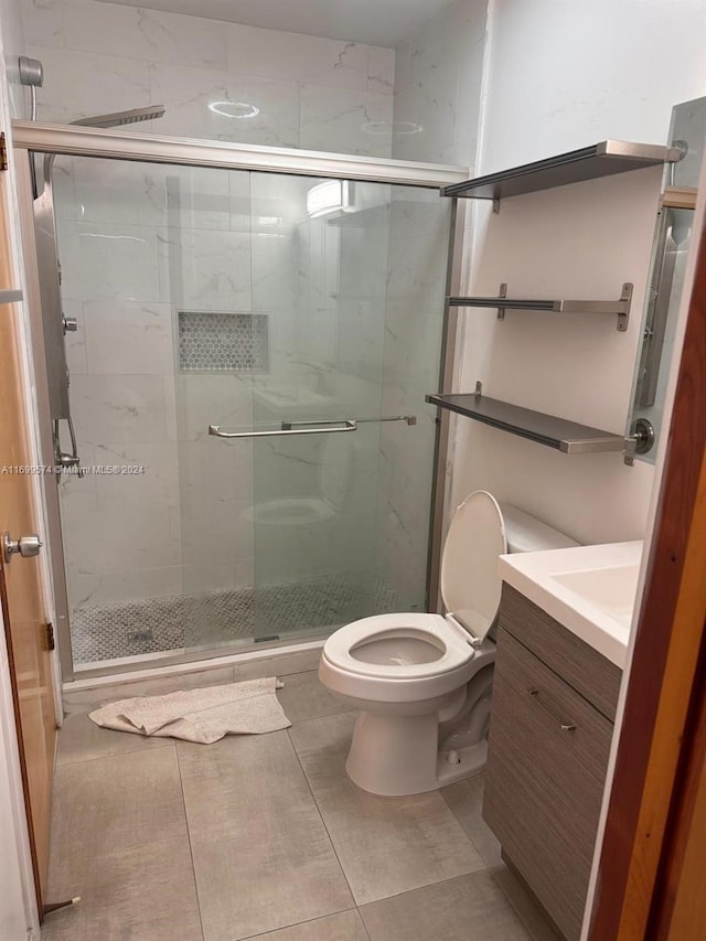 bathroom featuring tile patterned floors, vanity, toilet, and an enclosed shower