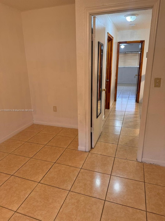 corridor featuring light tile patterned floors and a textured ceiling