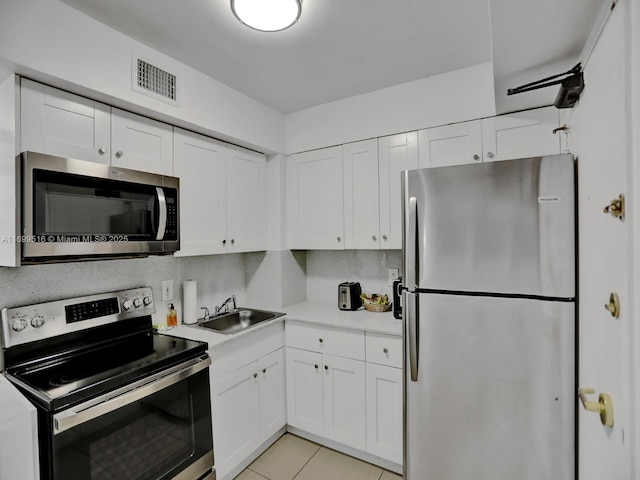 kitchen with white cabinetry, sink, light tile patterned floors, and stainless steel appliances