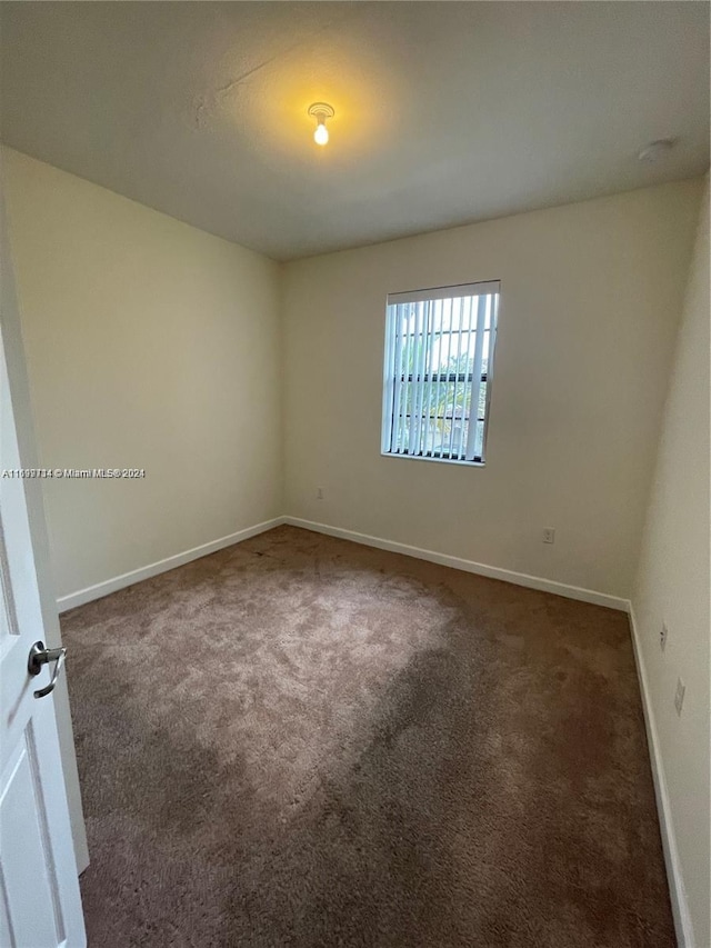 unfurnished room with dark carpet