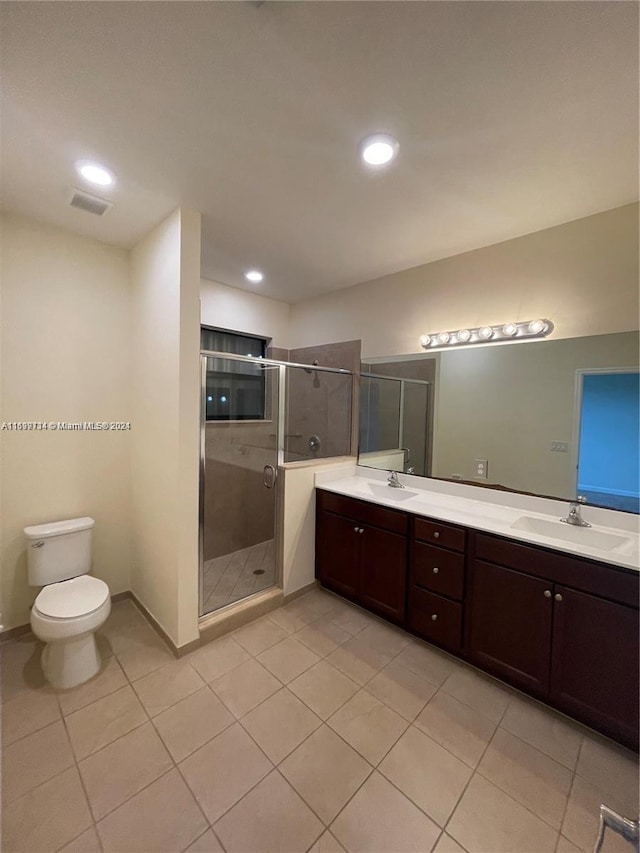 bathroom featuring tile patterned flooring, vanity, toilet, and an enclosed shower