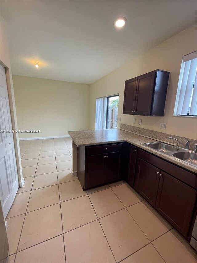 kitchen with dark brown cabinets, kitchen peninsula, sink, and light tile patterned floors