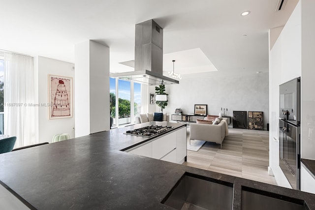 kitchen with white cabinets, decorative light fixtures, island range hood, and stainless steel gas cooktop