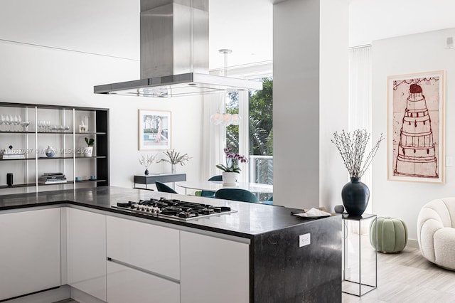 kitchen featuring island exhaust hood, light hardwood / wood-style flooring, and stainless steel gas stovetop