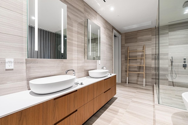 bathroom with vanity, tile walls, and a shower with shower door