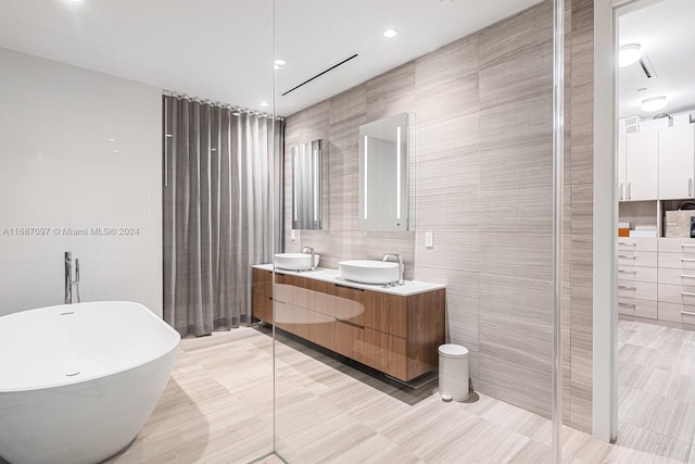 bathroom with tile patterned flooring, vanity, tile walls, and a bathing tub