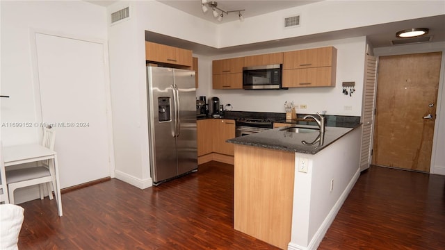 kitchen featuring sink, dark hardwood / wood-style floors, kitchen peninsula, dark stone counters, and appliances with stainless steel finishes