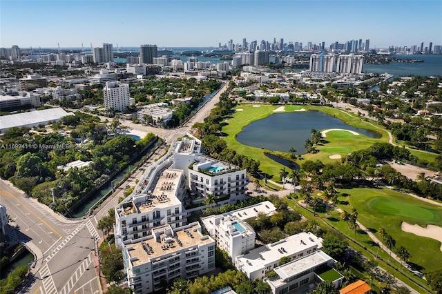 drone / aerial view featuring golf course view, a water view, and a city view